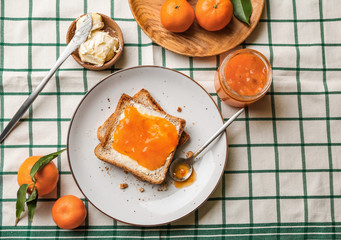 Bread with butter and tasty tangerine jam on table