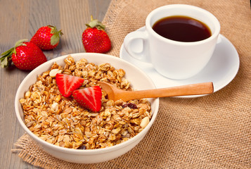 A plate with muesli, strawberries and cup of coffee on the wooden table