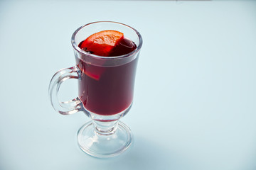 Wineglass with Christmas mulled red wine with spices and fruits on a blue background.