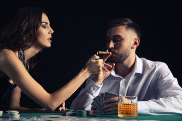 Woman giving light to poker player in casino