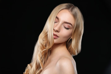 Naklejka premium Young woman with beautiful curly hair on dark background