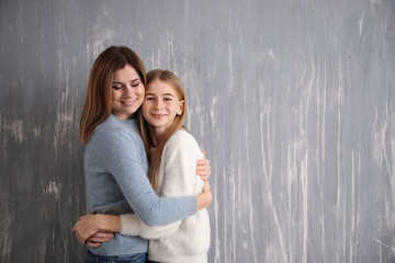 Portrait of happy mother and daughter on grey background