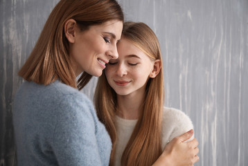 Portrait of happy mother and daughter on grey background