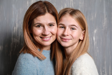 Portrait of happy mother and daughter on grey background