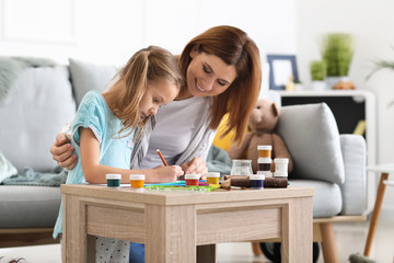 Happy mother with daughter painting at home