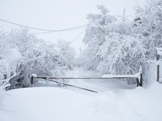 The snow-covered road is closed by a barrier and it is impossible to pass