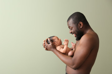 Naklejka premium Portrait of happy African-American father with little baby on color background