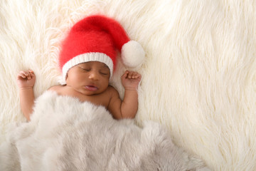 Fototapeta premium Cute African-American baby in Santa Claus hat sleeping on white furry plaid