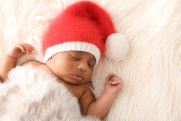 Fototapeta premium Cute African-American baby in Santa Claus hat sleeping on white furry plaid