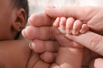 Cute little baby holding mother's finger, closeup