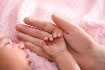 Cute African-American baby with mother's hand on soft plaid, closeup