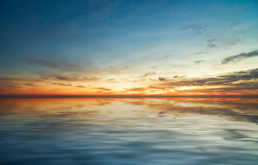 Fototapeta na wymiar Magnificent bright sunset over the calm surface of the sea.