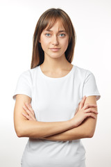Fototapeta premium Studio shot of brunette fit woman with slender legs, wears casual white t shirt and pants, demonstrates healthy lifestyle, looks confidently at camera, has healthy cared skin and hair