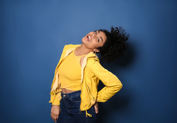 Portrait of young African-American woman on color background