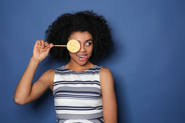 Portrait of young African-American woman with lollipop on color background