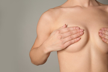 Naked woman on grey background. Concept of breast augmentation