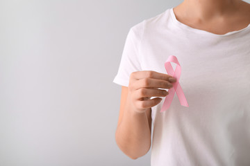 Woman with pink ribbon on light background. Breast cancer awareness concept