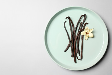 Plate with aromatic vanilla sticks on white background