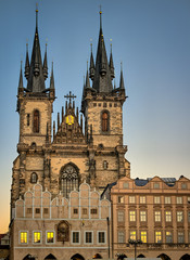Fototapeta premium Church of Our Lady before Týn, an ornate gothic medieval catholic church with towers and spires, behind cafes in the Old Town Square, Prague, Czech Republic with golden sunset reflected in the windows