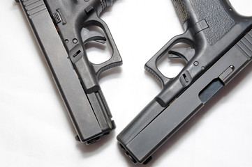 Two black semi automatic pistols, a 9mm and a 40 caliber on a white background showing the different sizes of them