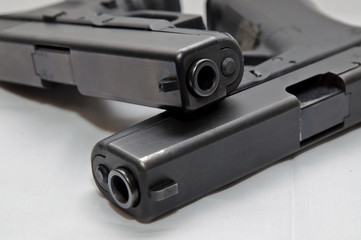 Two black semi automatic pistols, a 9mm and a 40 caliber with one on top of the other on a white background