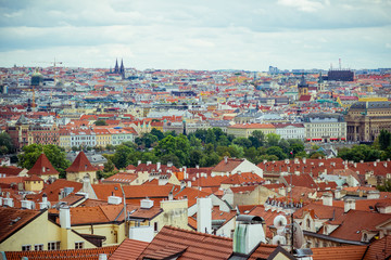 Fototapeta na wymiar Elevated view over the rooftops and cityscape of Prague on a dull day. Shows the bright colourful buildings, the churches, architecture, statues and monuments.