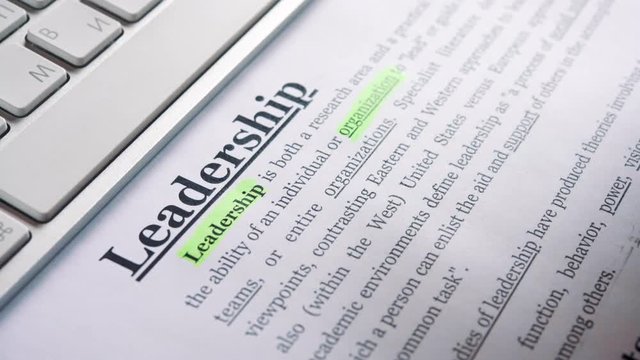A businessman highlights the definition of the word leadership with a marker in the text. Very smooth dolly shot 4K video with shallow depth of field focus.