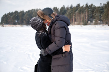 Fototapeta na wymiar Young millennial couple in love embracing in winter park outdoor. Sensual tender boyfriend and girlfriend enjoying romantic moment together, feeling intimacy and closeness.