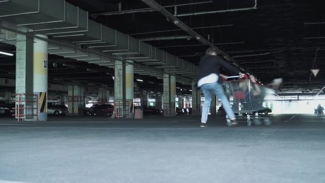 The Man Rolls The Girl In The Trolley From The Supermarket In The Underground Parking