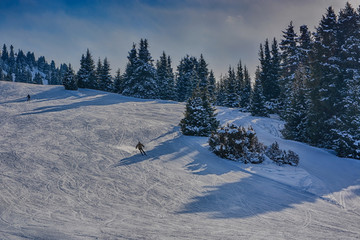 Fototapeta na wymiar Winter landscape with snow, forest and skiers in Karakol, Kyrgyzstan.