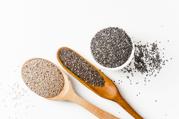 Black and white chia seeds superfood in wooden spoons on white background