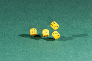 Four yellow dices falling on a green table