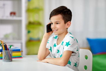 people, technology and communication concept - happy smiling boy calling on smartphone at home