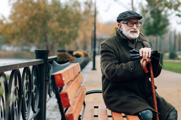 Kind grey-haired male person having rest during walk