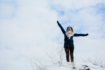 girl in winter stands on a hill with his hands up. concept of freedom or victory