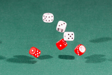 Six red and white dices falling on a green table