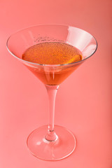 Glass with cocktail on coral background