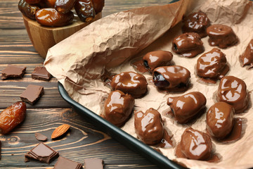 Sweet dried dates covered with chocolate on baking tray