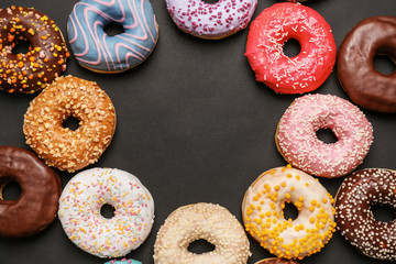 Frame made of sweet tasty donuts on dark background