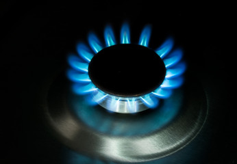  The gas is burning, the gas-stove burner, the hob in the kitchen, close-up. The concept of problems with natural gas