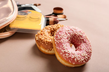 Sweet tasty donuts and cosmetics on color background