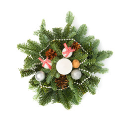 Christmas decoration consisting of fir twigs, shiny balls, cones around the candle, without snow on a white background. Top view