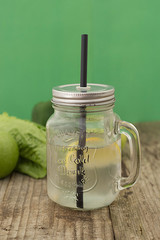 Lemonade with lemon, tonic drink, mint in a mason jar on a wooden rustic table and green background. Green fresh food background.