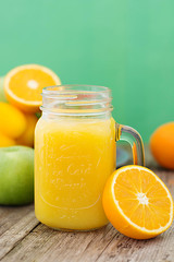 Fruit juice in the glass jar. Green background, wooden table. Fresh vegetables and fruits - avocado, apple, tomatoes. . Healthy, vegan food and drinks.