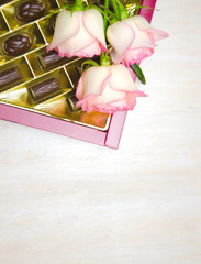 candy and roses on white wooden background
