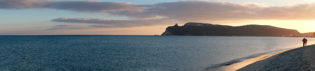 super panorama of the main beach of Cagliari (poetto sella del diavolo) with two walking lovers at...