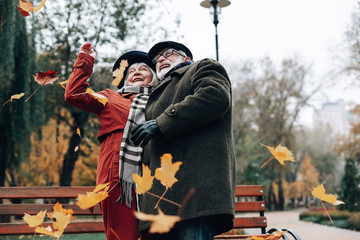 Positive delighted senior people looking at flying leaves