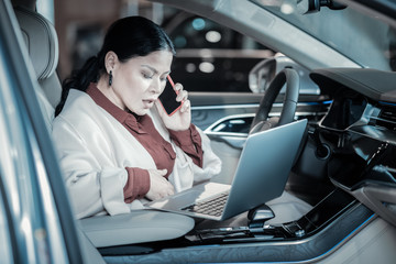 Successful mature businesswoman using her laptop while sitting in car