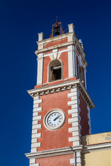 Fototapeta premium Clock tower, red with white bricks. The building dates back to the nineteenth century. Bells on the top. Cerignola, Puglia, Italy.