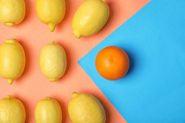 Orange in front of lemons on color background, top view. Be different